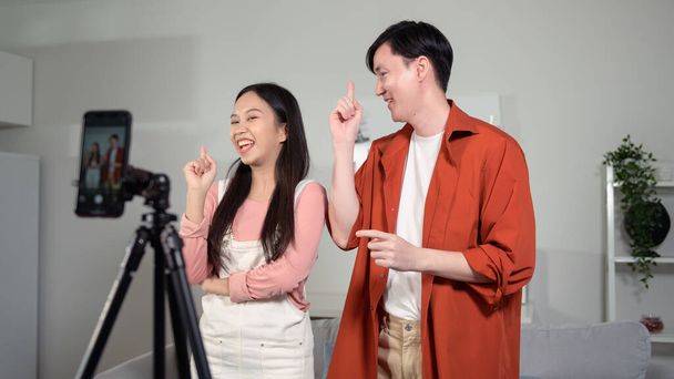 Asian young couple tiktokers are making video dancing  via smartphone together,  share video content on social media.  - Valokuva, kuva