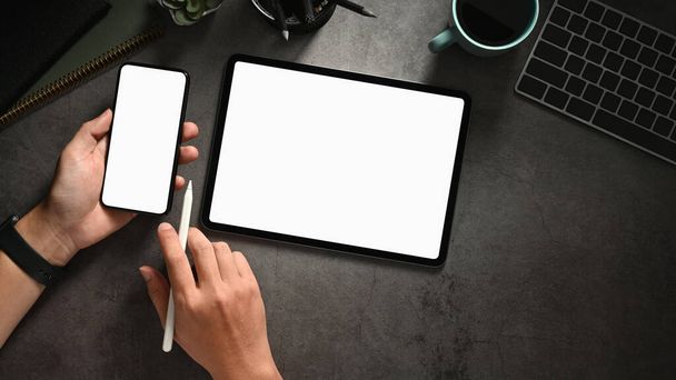 Top view irodai íróasztal kezében intelligens telefon és tabletta, üres képernyős okostelefon és tabletta a jelen. Kiváló minőségű fénykép - Fotó, kép