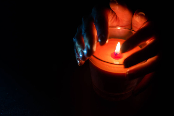 La vela está encendida en un vaso sostenido por una hermosa mujer de negro. Aislado en el concepto de ahorro de energía de las tierras. Hora de la Tierra. - Foto, imagen