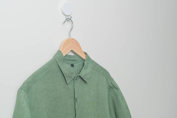 hanging green shirt with wood hanger on wall - Valokuva, kuva