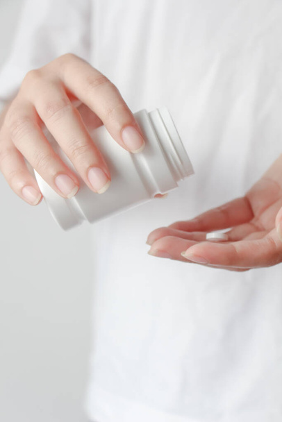 Close up de mãos femininas derramando comprimidos de medicamentos do frasco em sua mão - Foto, Imagem