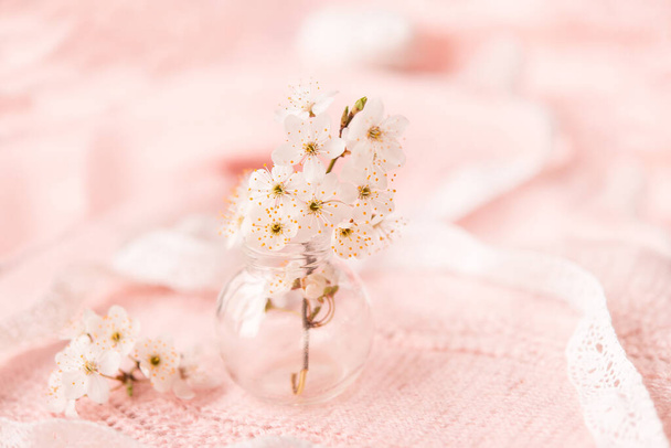 cherry blossoms in a small glass vase on a delicate pink knitted background - Foto, imagen