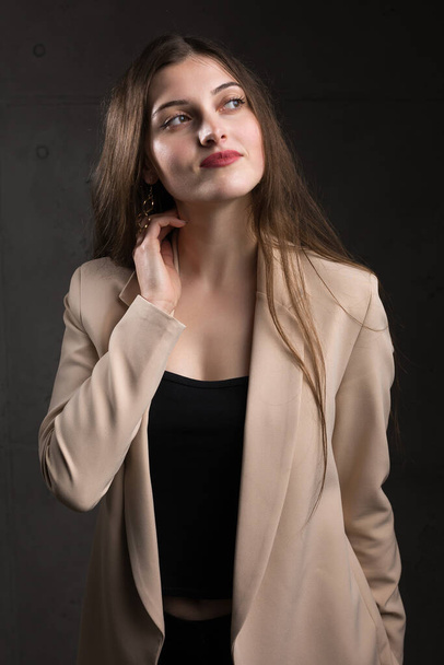 Portrait of a young brunette with long hair in the studio. Dramatic photo in dark colors. - Photo, Image