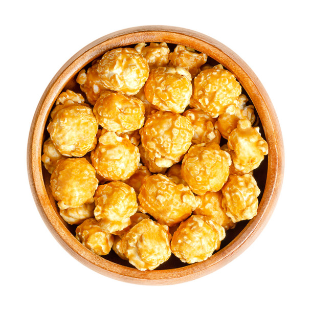 Karamell-Popcorn, Karamell-Mais oder auch Toffee-Popcorn, in einer Holzschüssel. Konfekt aus Popcorn mit Zucker oder Melasse auf Basis einer dünnen Schale aus Karamellbonbons. Süß aromatisierte, knusprige Snacks. - Foto, Bild
