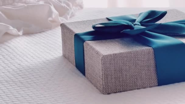Святковий подарунок і розкішна онлайн доставка покупок, загорнута лляна подарункова коробка з синьою стрічкою на ліжку в спальні, шикарний сільський стиль, крупним планом
 - Кадри, відео