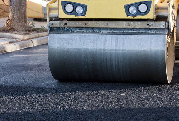 Rolo de estrada e máquina de pavimentação de asfalto no local de construção
 - Foto, Imagem