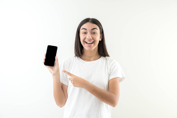 Junges Mädchen glückliches Lächeln, das gute Nachrichten oder Nachrichten auf dem Handy zeigt. Ausdruck der Freude über die auf dem Handy empfangene Nachricht. - Foto, Bild