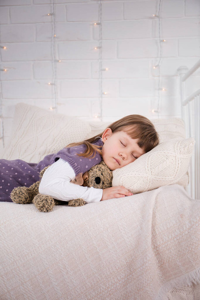 Dívka leží na staré posteli s pleteným spodním prádlem. Vánoční koncept - Fotografie, Obrázek