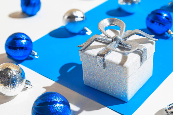 Composition créative faite de boîte cadeau en argent et des boules sur fond blanc et bleu avec des ombres. Noël et nouvelle année concept. Style minimal. - Photo, image