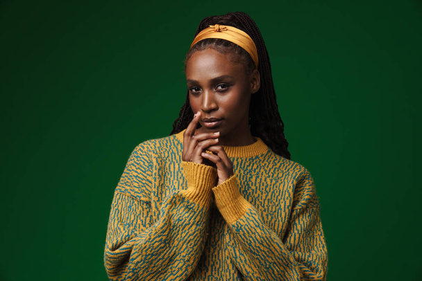 Young black woman wearing headband posing and looking at camera isolated over green wall - Foto, afbeelding