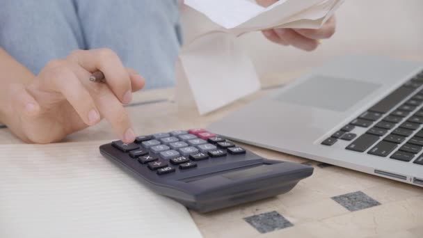 Closeup hands of woman calculating finance household with calculator on desk at home, girl checking bill for saving and planning expenses, debt and loan, tax and accounting, business and financial. - Footage, Video