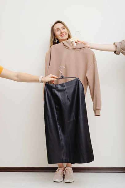Twee handen die kleren vasthouden aan hangers voor vrouwen. Fashion shopping concept. - Foto, afbeelding