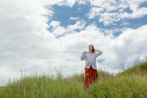 beautiful girl in white shirt and orange skirt against blue sky and clouds close up - Photo, Image