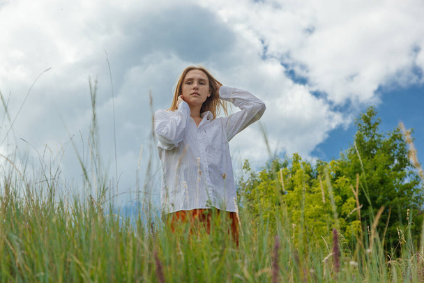 krásná dívka v bílé košili a oranžové sukně proti modré obloze a mraky zblízka - Fotografie, Obrázek