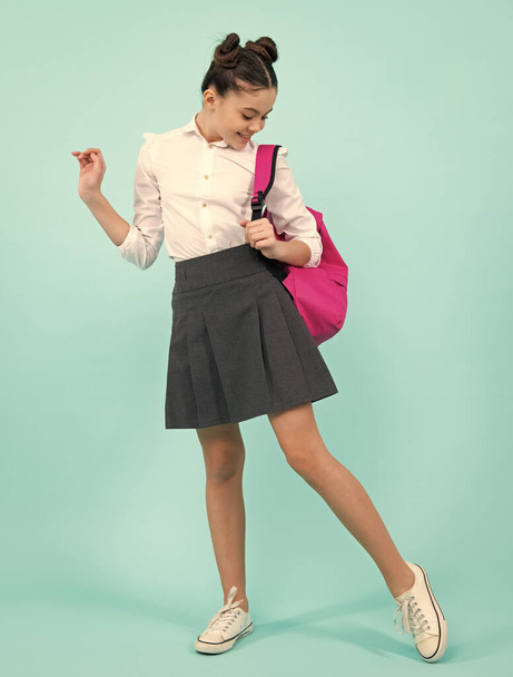 Chica de la escuela en uniforme escolar con mochila. Adolescente estudiante sobre fondo azul aislado. Conocimiento de aprendizaje y concepto de educación para niños. Adolescente de cuerpo entero, colegiala - Foto, imagen