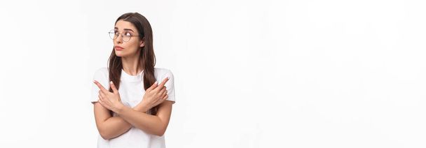 Портрет талії нерішучої молодої жінки в окулярах, 20-річна студентка, яка вибирає свій шлях, вказуючи пальці в сторону ліворуч і праворуч, приймаючи рішення, думаючи на білому тлі
. - Фото, зображення