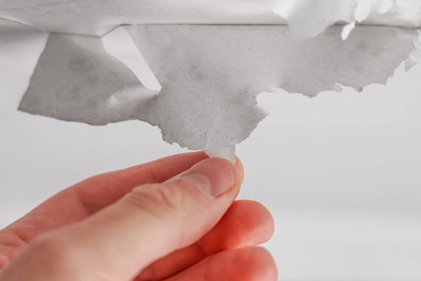 Removing a layer of old white paint from the ceiling by hand close-up. Peeling whitewash - Foto, Imagem