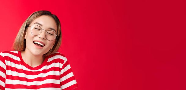 Feliz soñador alegre chica asiática sentirse bien relleno después de comer sándwich favorito, mujer usar gafas cerrar los ojos encantado sonriendo ampliamente abierto boca fantaseando, soñando sabrosa hamburguesa. - Foto, Imagen