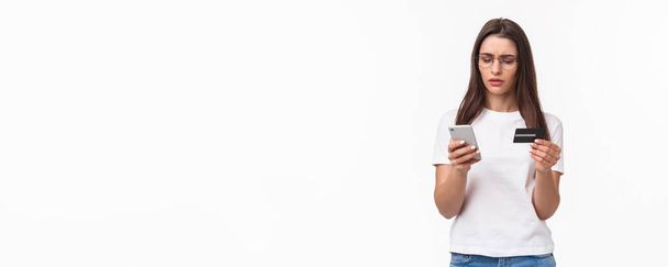 Retrato de olhar sério, focado jovem atraente mulher copiando números de dígitos do cartão de crédito em informações de faturamento no aplicativo, pagando ou produtos on-line, compra na loja de internet com smartphone. - Foto, Imagem