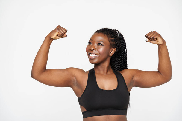 Young black sportswoman with afro pigtails showing her biceps isolated over white background - Foto, Imagem