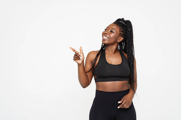 Black young woman smiling and pointing finger aside isolated over white background - Foto, immagini