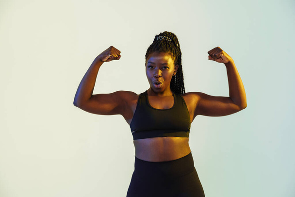 Black young sportswoman showing her biceps at camera isolated over white background - Fotoğraf, Görsel
