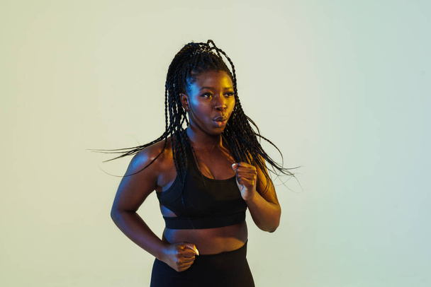 Black young woman with afro pigtails running while working out isolated over white background - Photo, image