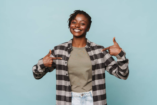 African american young woman wearing plaid shirt smiling and gesturing at herself isolated over blue background - Valokuva, kuva