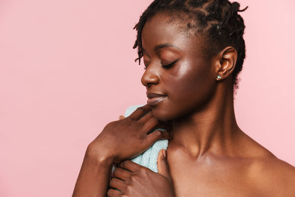 Black shirtless woman posing with blue towel on camera isolated over pink background - Foto, Imagem