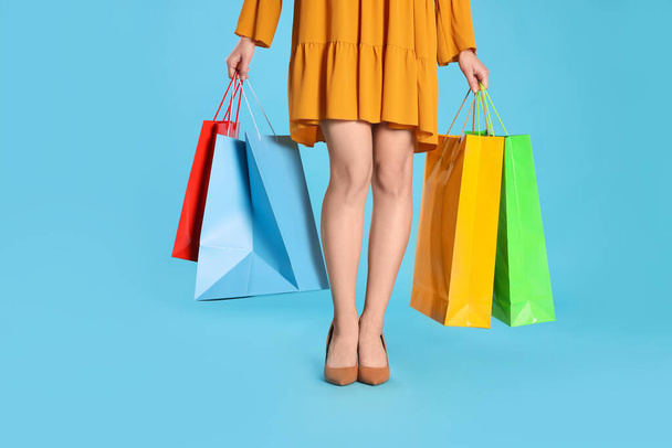 Woman holding shopping bags on light blue background, closeup. Big sale - Photo, Image