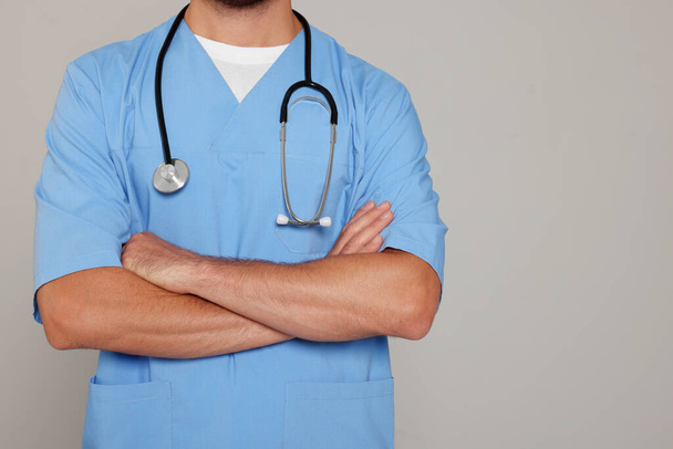 Doctor with stethoscope on light grey background, closeup - Fotó, kép