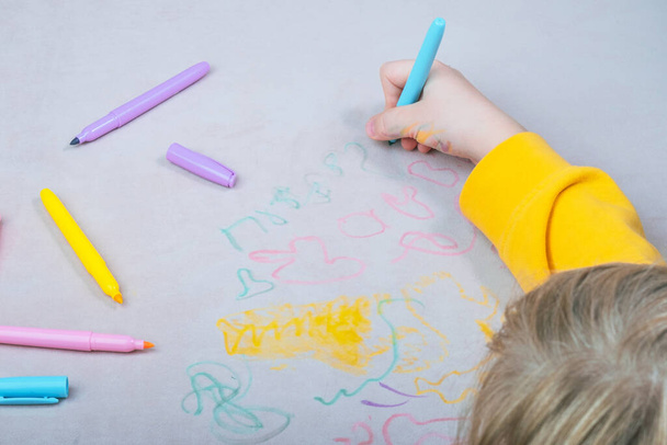 Дитяча рука малює ручкою з фетровою ручкою на оббивці дивана. вид зверху. Меблева тканина. Концепція очищення. Високоякісна фотографія
 - Фото, зображення