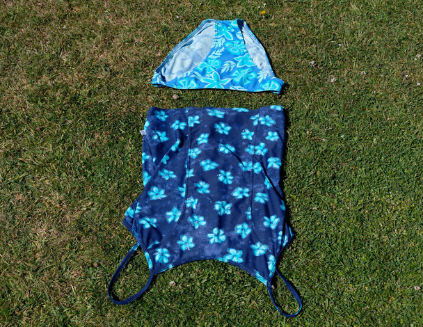 Una suite de natación de dos piezas se ha puesto en la hierba para secarse después de nadar - Foto, Imagen