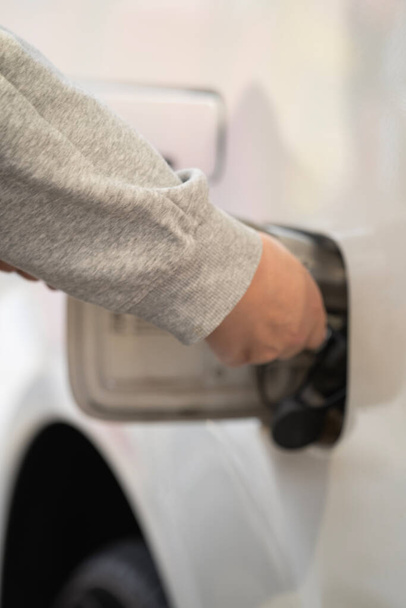 Primer plano de una mano abriendo los coches tapa del tanque de combustible en coche blanco. Repostar un coche en una gasolinera - Foto, Imagen