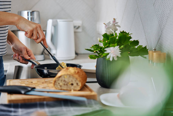 Kadının mutfakta kahvaltı hazırlama süreci. Kızartma tavasında omlet hazırlayan kadın elleri, indüksiyon sobası kullanıyor. - Fotoğraf, Görsel