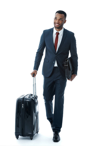 Looking forward to the day. A handsome young african american businessman walking alongside his suitcase while isolated on white - Photo, Image