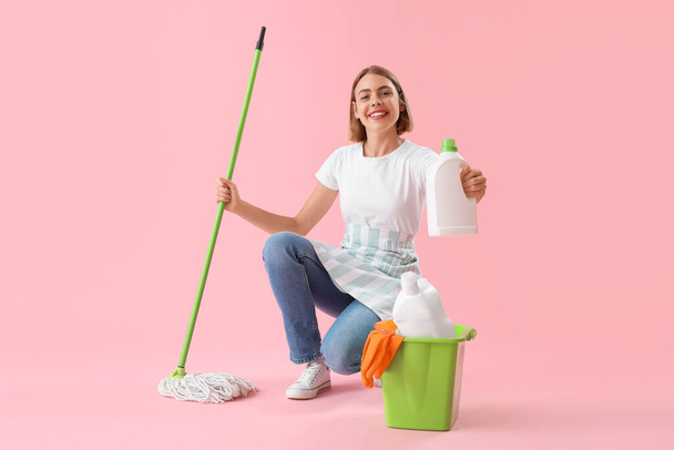 Mujer bonita con artículos de limpieza sobre fondo rosa - Foto, imagen