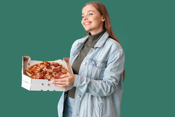 Krásná mladá žena držení box s čerstvou pizzu na zeleném pozadí - Fotografie, Obrázek