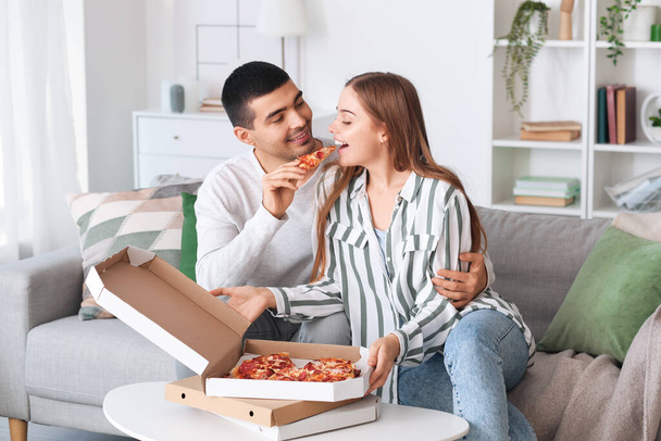 Joyeux jeune couple mangeant de délicieuses pizzas à la maison - Photo, image