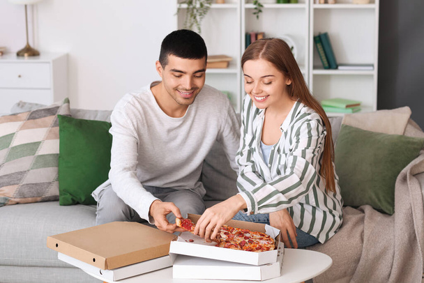Feliz joven pareja comiendo sabrosa pizza en casa - Foto, Imagen
