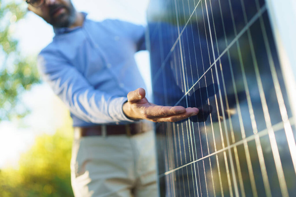 Businessman holding and explaining how solar panel works, standing outdoor at a garden. - Foto, imagen