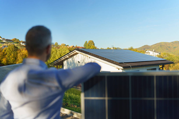 Businessman holding a solar panel, standing outdoor at a garden. - Φωτογραφία, εικόνα