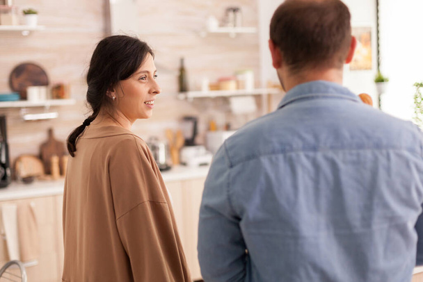 Дружина дивиться на чоловіка на кухню, що прибуває з супермаркету. Здорові щасливі стосунки спосіб життя чоловіка і жінки, разом покупки продуктів
 - Фото, зображення