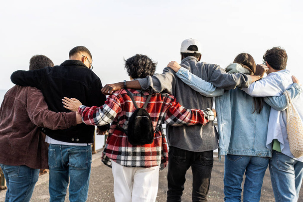 Unite group of multiethnic young friends walking outdoors hugging together - unity, oneness, youth hipster culture, solidarity, equality and international teamwork concept - Photo, Image