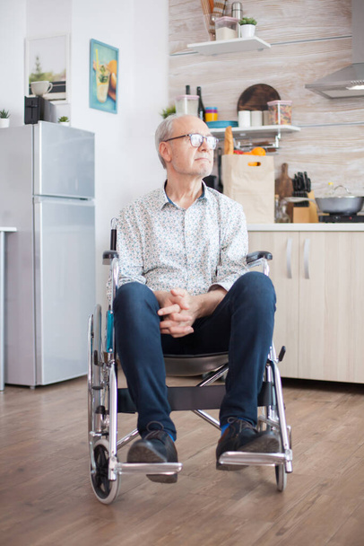 Pensionista discapacitado solitario en silla de ruedas preocupado por su vida. Anciano pensionista discapacitado después de lesiones y rehabilitación, parálisis y discapacidad para deprimido inválido lleno de dolor, preocupación y tristeza - Foto, Imagen