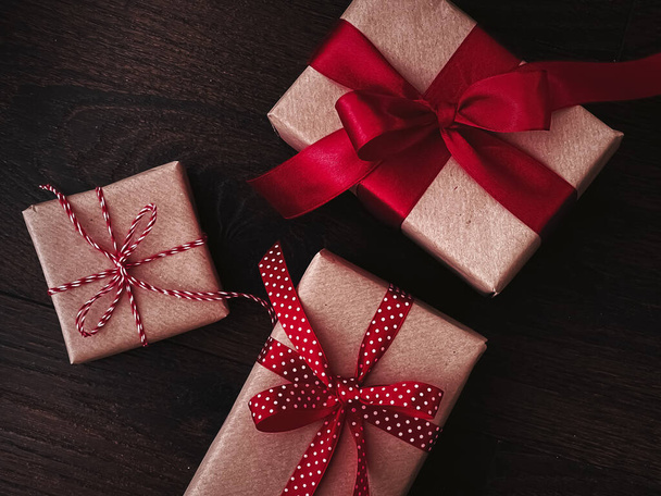 Karácsonyi ajándékok és hagyományos ünnepi ajándékok, klasszikus karácsonyi ajándékdobozok fából készült háttér, jelen csomagolva kézműves papír piros szalaggal, vintage rusztikus vidéki stílus szezonális nyaralás - Fotó, kép