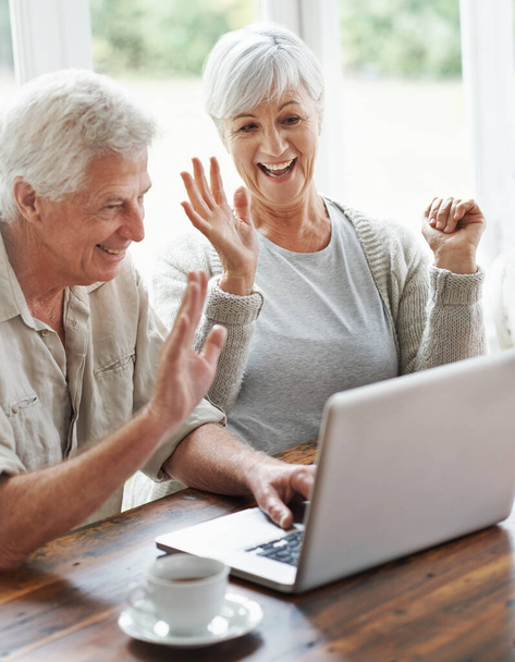 Es genial ver a los nietos. Una alegre pareja de ancianos teniendo un video chat en un portátil - Foto, Imagen