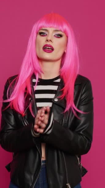 Függőleges videó: Fiatal női modell csinál imakéz és könyörög a jó szerencsét, miután a hit és imádkozik rózsaszín háttér. Vonzó felnőtt bőrdzsekiben, aki szerencsét és hitet kér. - Felvétel, videó