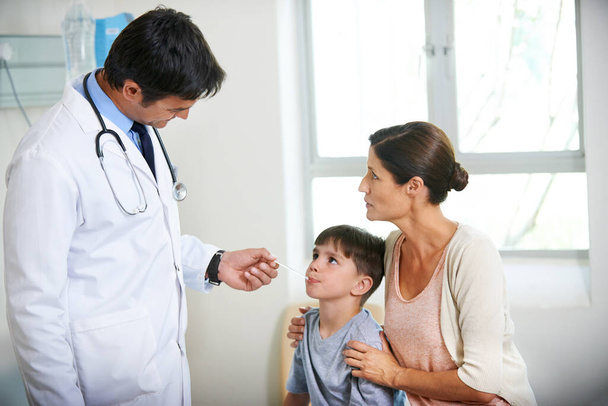 Youre going to be just fine. The family doctor takes a young boys tempreture while his mother holds him - Фото, зображення