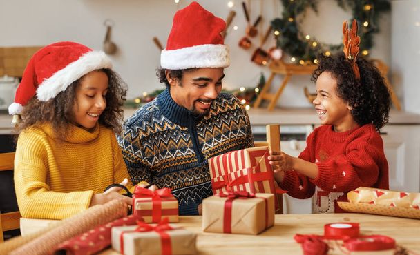 Χαρούμενη αφροαμερικάνικη οικογένεια πατέρας και παιδιά κόρη και γιος πακέτο χριστουγεννιάτικα δώρα - Φωτογραφία, εικόνα